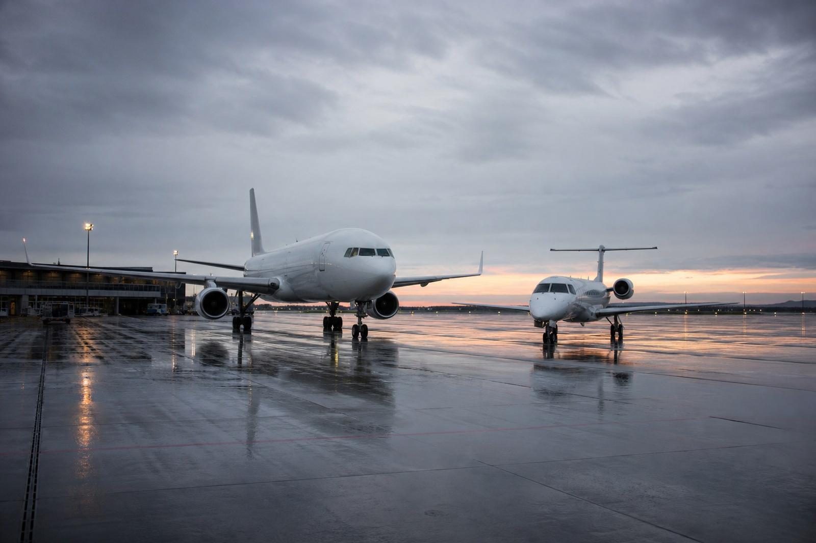 A large narrow-body aircraft and a smaller regional jet on an airport apron at dawn.