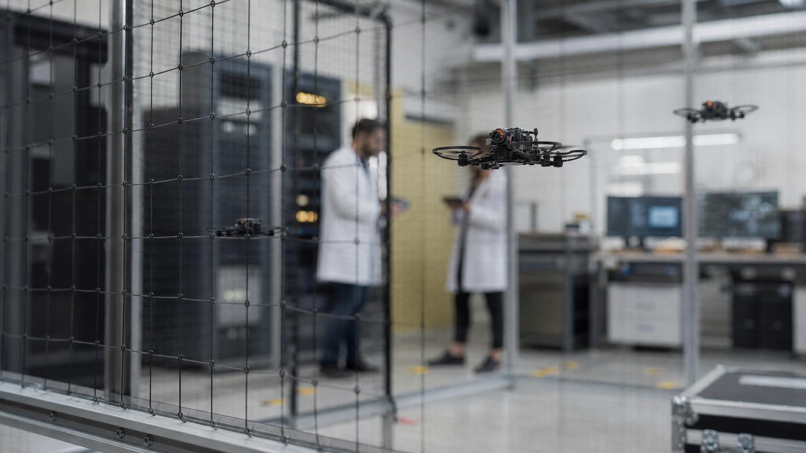 Small drones flying inside a secure robotics laboratory.